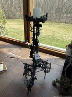 Full view of artistic metal candle holder standing near window, showing structure and lights.