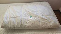 Duvet folded neatly on a bed showcasing its white fabric and size