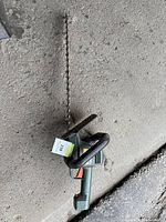 Top down view of electric bush trimmer showing the long serrated metal blade and front handle.