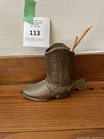 Side view of brass cowboy boot figurine showing spiked spur and detailed stitching