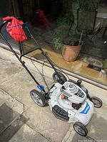 Oblique side view of mower showing handle, deck and wheels