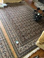 Full view of the large rectangular oriental style area rug on hardwood floor near stone fireplace and furniture.