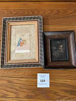 Two framed oriental art pieces on wooden floor with lot number card below