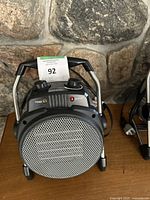 Front view of the Almio portable heater showing round metal grill and control panel with knobs and indicator lights.