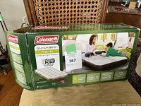 Box front showing Coleman Quickbed twin size single high airbed with included pump and usage image.