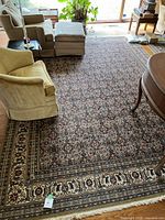 Full view of the decorative area rug laid out in a living room with furniture around it, showing the overall pattern and condition.