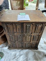 Front view of the wooden smoking pipe cabinet showing carved panel doors and wood texture with wear and stains.