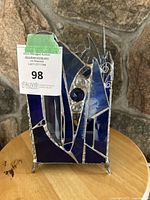 Front view of the stained glass candle holder highlighting the blue and purple glass panels and central clear glass spheres.