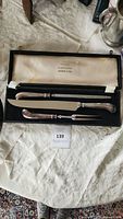Full view of 3-piece silver-plated carving set in black case with white interior, knife, fork, and sharpening steel visible.