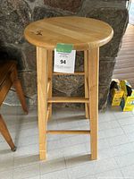 Front view of the solid wood stool showing the round seat, legs, and lower supports.