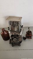Photo showing the group of antique items: Westinghouse toaster, Queen mini cast stove, mini coffee grinder, and copper bottle