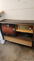 Wooden vintage console with radio and record player behind a sliding door