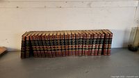 Photo of the complete 24-volume set of Funk & Wagnalls New Encyclopedia arranged upright showing spines with gold and red details.