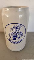 Front view of porcelain Octoberfest stein with blue cartoon character and text.