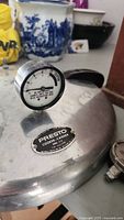 Close-up of pressure cooker lid showing Presto label and built-in pressure gauge.