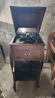 Full wooden cabinet phonograph with lid open displaying turntable and tonearm