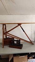 Vintage Singer sewing machine and antique ironing board displayed on table