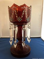 Front view of the antique red crystal luster showing painted floral details and hanging clear crystal prisms.