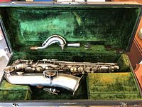 Overview of saxophone, detachable neck, mouthpiece, ligature inside green velvet-lined case