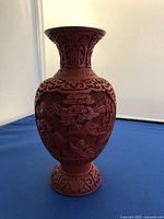 Full view of the cinnabar vase showing detailed floral and landscape carvings and the red lacquer surface.