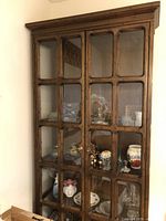 Front view of wooden display cabinet with visible glass-paned double doors and interior contents.