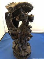 Front and side view of detailed wooden sculpture showing mythical figure on a winged beast with claws and sharp teeth.