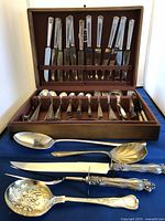 Full view of silverware set in original wooden case with some serving utensils displayed outside the case.