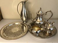 All pieces of the tea set displayed including the pewter pitcher and the larger tray.