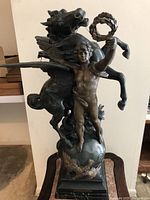 Front view of entire bronze sculpture showing male figure and winged horse