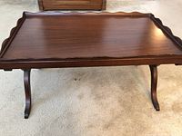 Top view showing rectangular wooden table surface with scalloped decorative edges and rich dark brown finish.