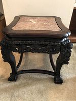 Victorian style side table showing front angle with pink marble inset top, dark carved wooden frame and legs with floral decorations and claw feet.