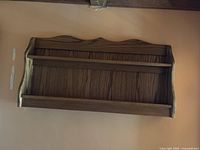 Brown wooden wall-mounted shelf with two shelves, photographed against a peach-colored wall from different angles to show design and condition.