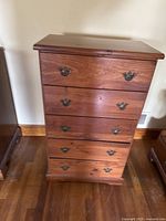 Front view of the five-drawer wooden chest showing brass hardware and minor surface scratches.