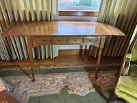 Full view of the wooden drop-leaf table showing top, legs, and drawer in light brown finish.