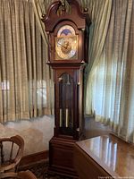 Full front view of wooden grandfather clock in dark brown finish