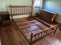 Full view of the full-size wooden bed frame with headboard and footboard, next to a matching nightstand and dresser.