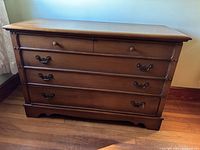Front view of vintage brown wooden Lane hope chest with one drawer and metal handles below drawer.
