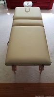 Full-length top view of beige massage table on wooden legs