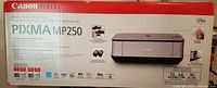 Photo of the front side of the sealed Canon PIXMA MP250 printer box showing the model, photo of the printer, and feature icons.