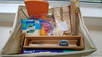 Photo showing assorted wood craft supplies including wooden sticks, beads, colorful pipe cleaners, foam sheets, and a wooden box labeled Premier.