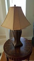 Photo of a brown wooden table lamp with pleated beige fabric shade.