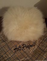 Photo of vintage white fur hand warmer with Holt Renfrew branding fabric beneath.