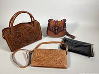 Photo showing all four purses arranged together: brown embossed leather handbag with handles, tan and reddish leather boho shoulder bag, snakeskin textured purse, and black patent clutch.
