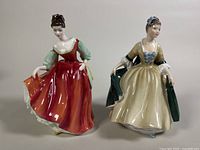 Front view of both Royal Doulton figurines Elegance and Fair Lady, showing detailed facial features and colorful dresses.