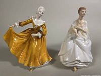 Front view of two Royal Doulton figurines, Megan in yellow dress and Kirsty in white gown