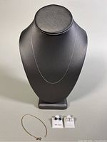 Photo showing the display stand with choker chain on and the earrings and bracelet laid out in front.