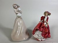 Front view of both Royal Doulton figurines showing 'Dreaming' in pastel pink and 'Top o the Hill' in red dress