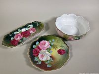 Full set of three antique hand-painted Royal Vienna porcelain pieces showing floral motifs and scalloped edges.