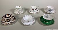 Front view of all six assorted bone china teacups and saucers arranged in a single line.