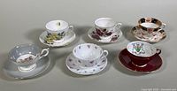 Six assorted bone china teacups and saucers shown together, varying floral and decorative patterns visible.